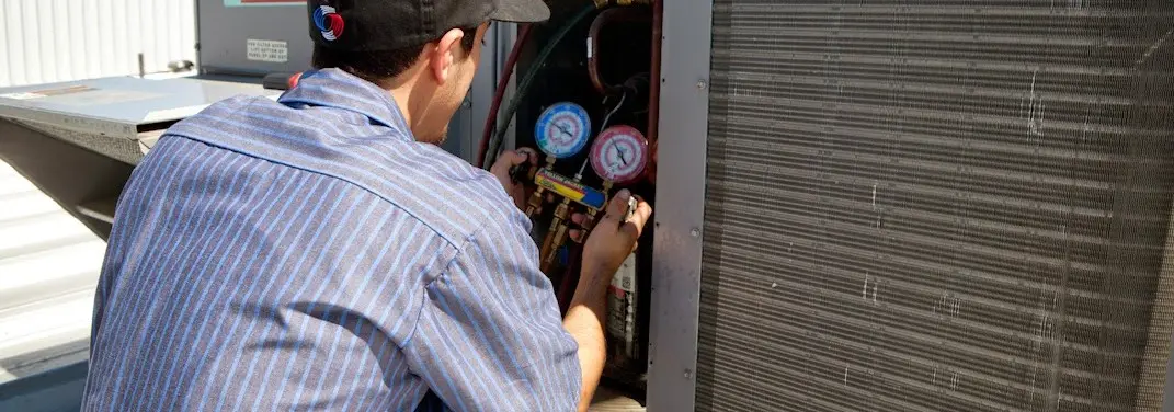 HVAC technician servicing a condenser unit in Athens